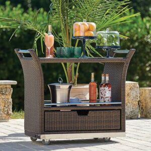 Outadore Space wicker serving cart with drinks, fruits, and tableware displayed outdoors beside greenery