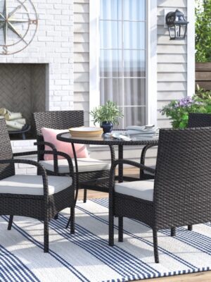 Outdoor rattan dining set with cushioned chairs and round table on a patio, crafted by Outadore Space